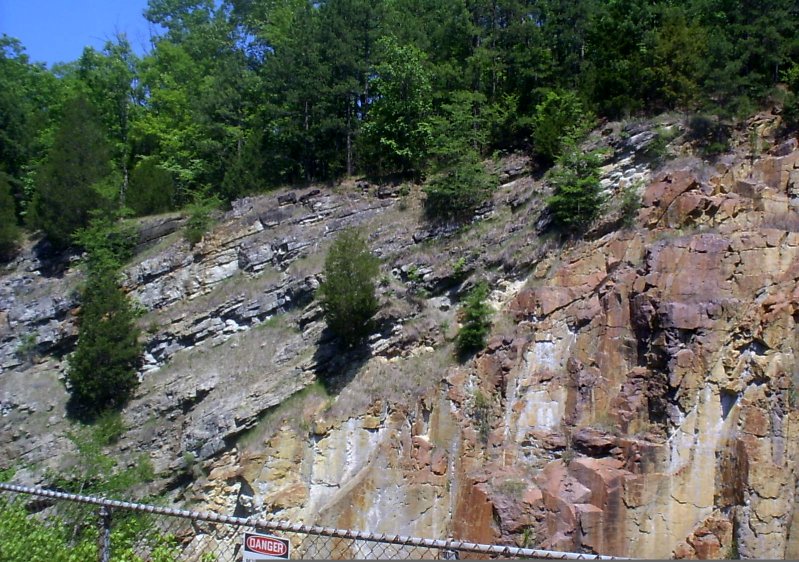 An exposed rock face where flat-lying layers rest on an irregular eroded surface of much older rock beneath them.